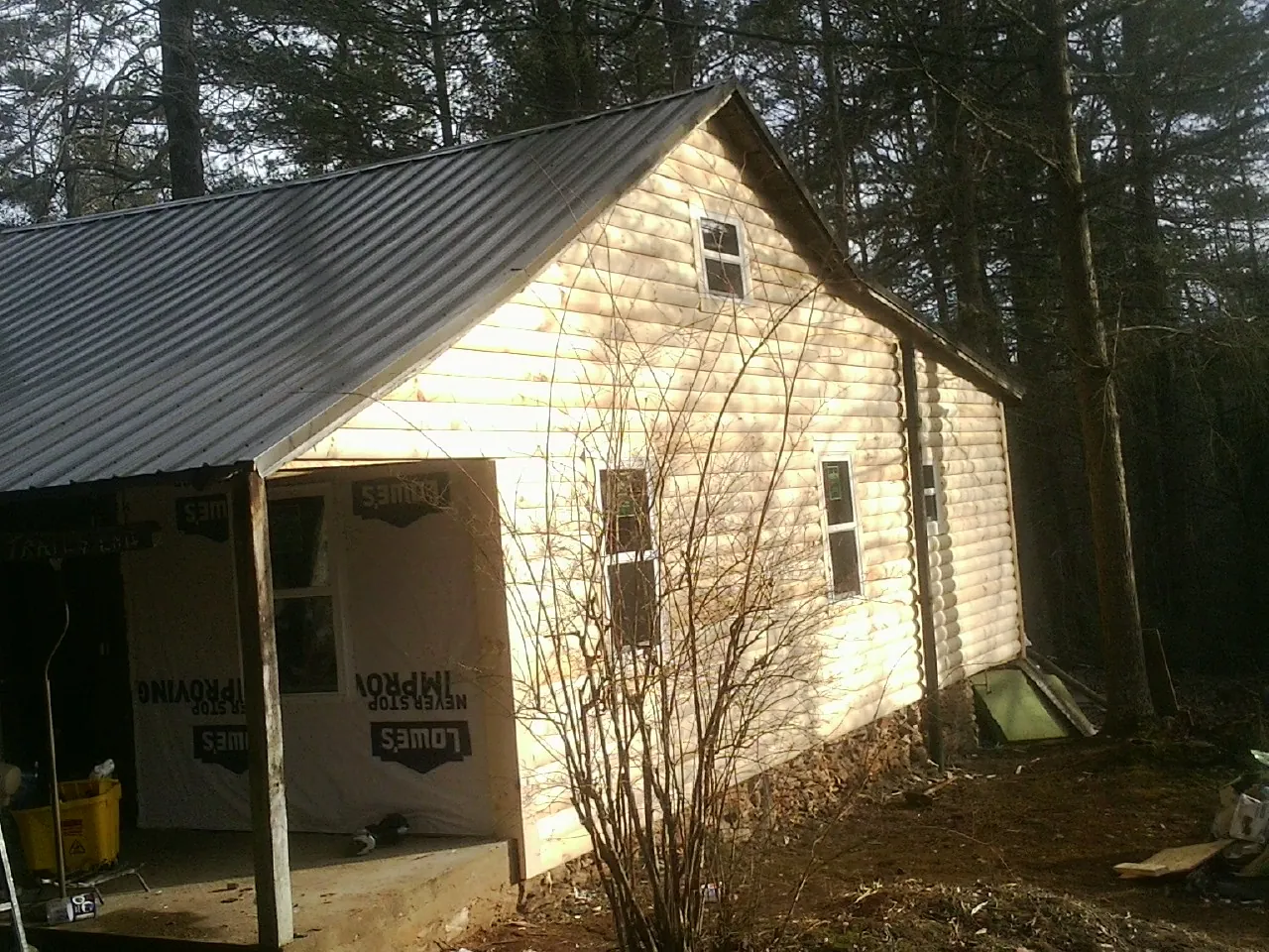 Log siding gable end under a dark metal roof edge in Feura Bush