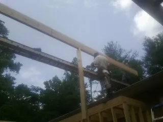 Carpenter setting a ridge beam over a new addition frame — Ice Dam Removal by Roofing Brothers in Feura Bush