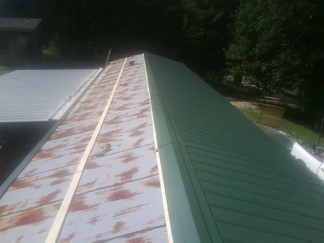 Old rusted panels beside newly installed green metal roofing — Wind Damage Roof Repair by Roofing Brothers in Feura Bush