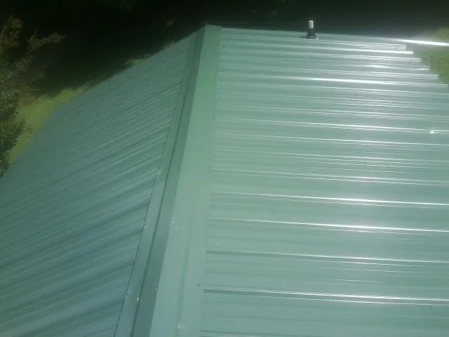 New green metal panels meeting at the ridge of a roof — Flat Roof Repair work by our crew in Feura Bush