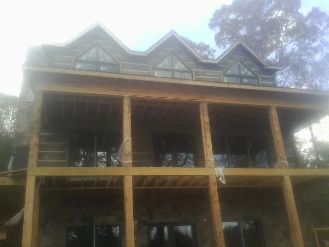 Dormers and porch framing on a large log home under construction — Roof Coating work by our crew in Feura Bush