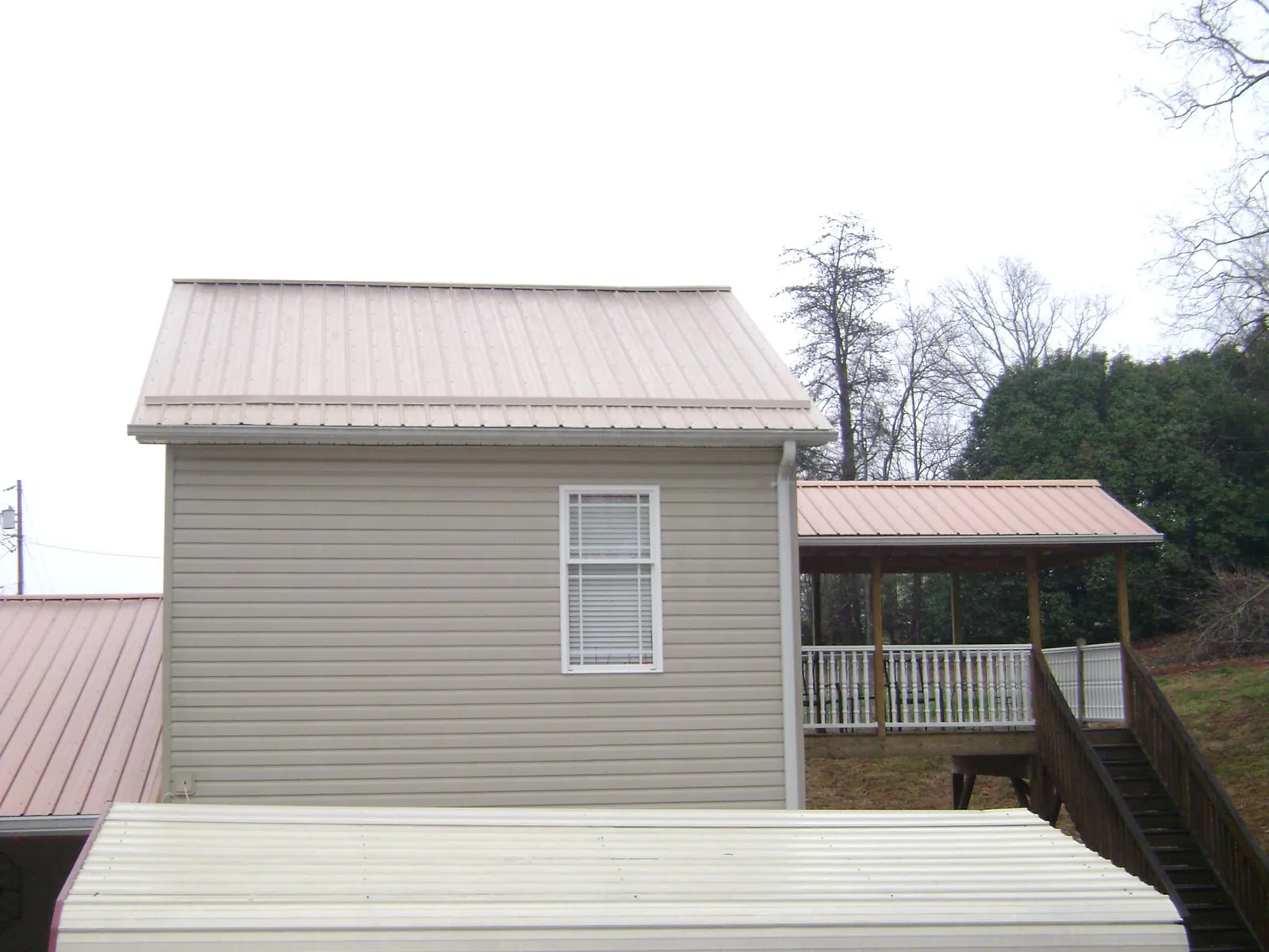 Tan metal roofs on a two story addition and attached porch, from a Roof Replacement job in Feura Bush