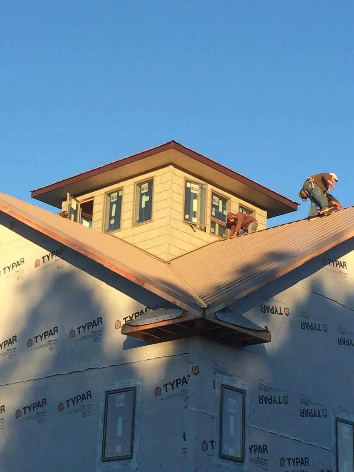 Roofers working around a rooftop cupola on a new metal roof at sunset — Roof Waterproofing in Feura Bush by Roofing Brothers